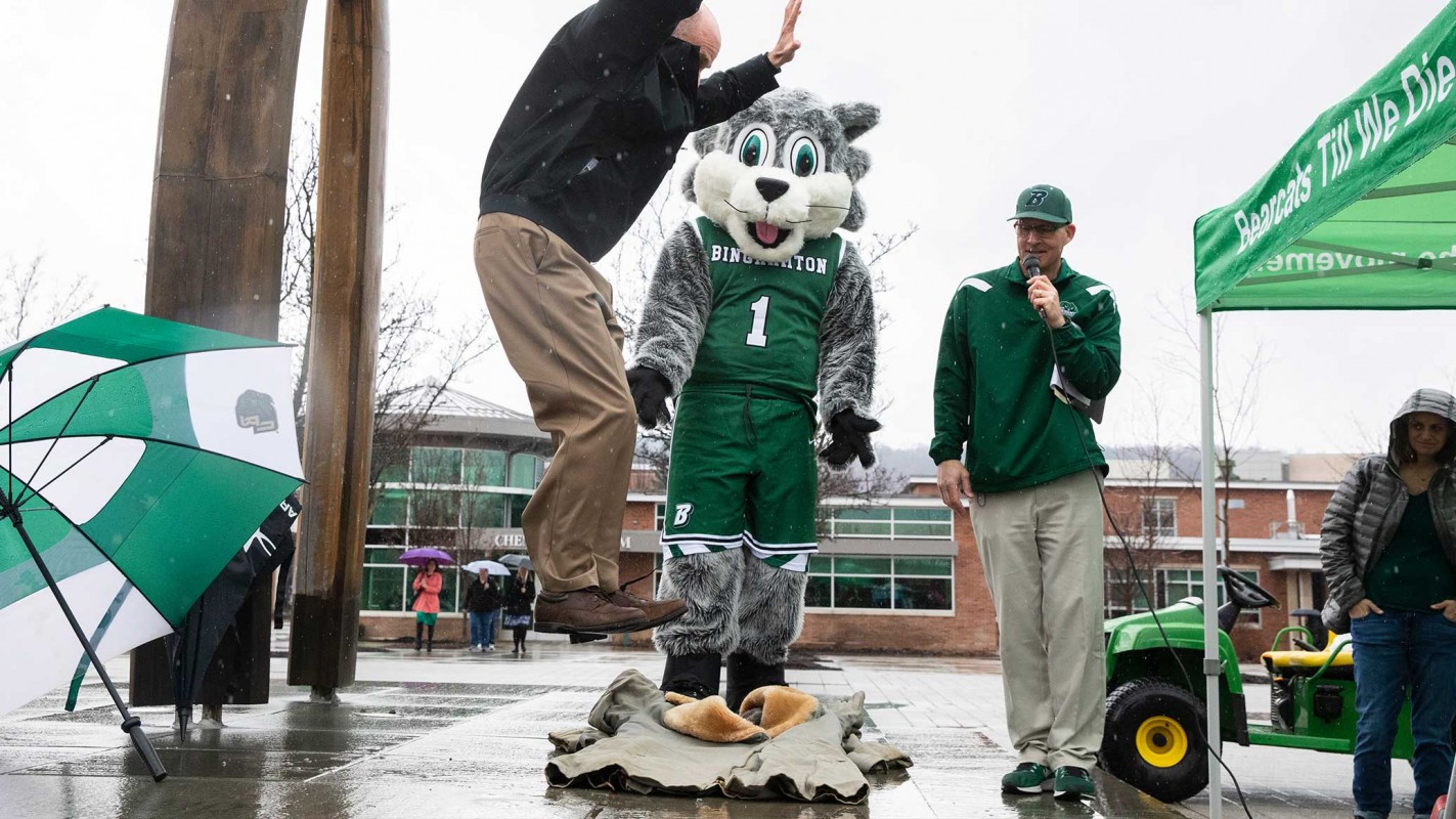 Vice President for Student Affairs Brian Rose steps (stomps!) on the coat during the 2019 ceremony. Dave Simek, associate director of athletics and chair of the campus Spirit Committee, and Baxter, look on.