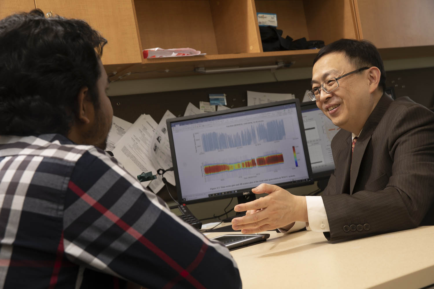 Ning Zhou, associate professor of electrical and computer engineering at the Watson School of Engineering and Applied Science, talks with his graduate student Tawsif Ahmad at his office in the Engineering and Science Building at the Innovative Technologies Complex.