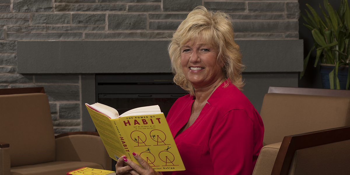 Kim Faber, executive director of alumni engagement, holding the virtual book club's first selection.