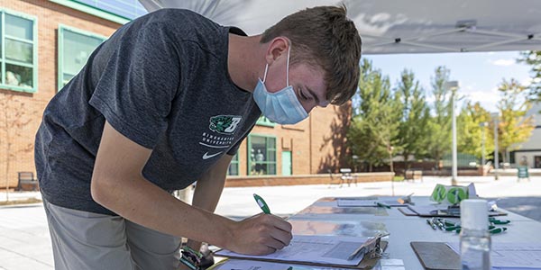 Incoming student Daniel Lounebery of Syracuse registers to vote at the Center for Civic Engagement table during Move-in Week Aug. 20, on the Spine, outside the entrance near the Bookstore.