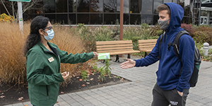 CCRT member Haleema Qamar hands first-year students Will Bezenah a voucher for a chance to win a prize at the University Bookstore for properly wearing his mask.