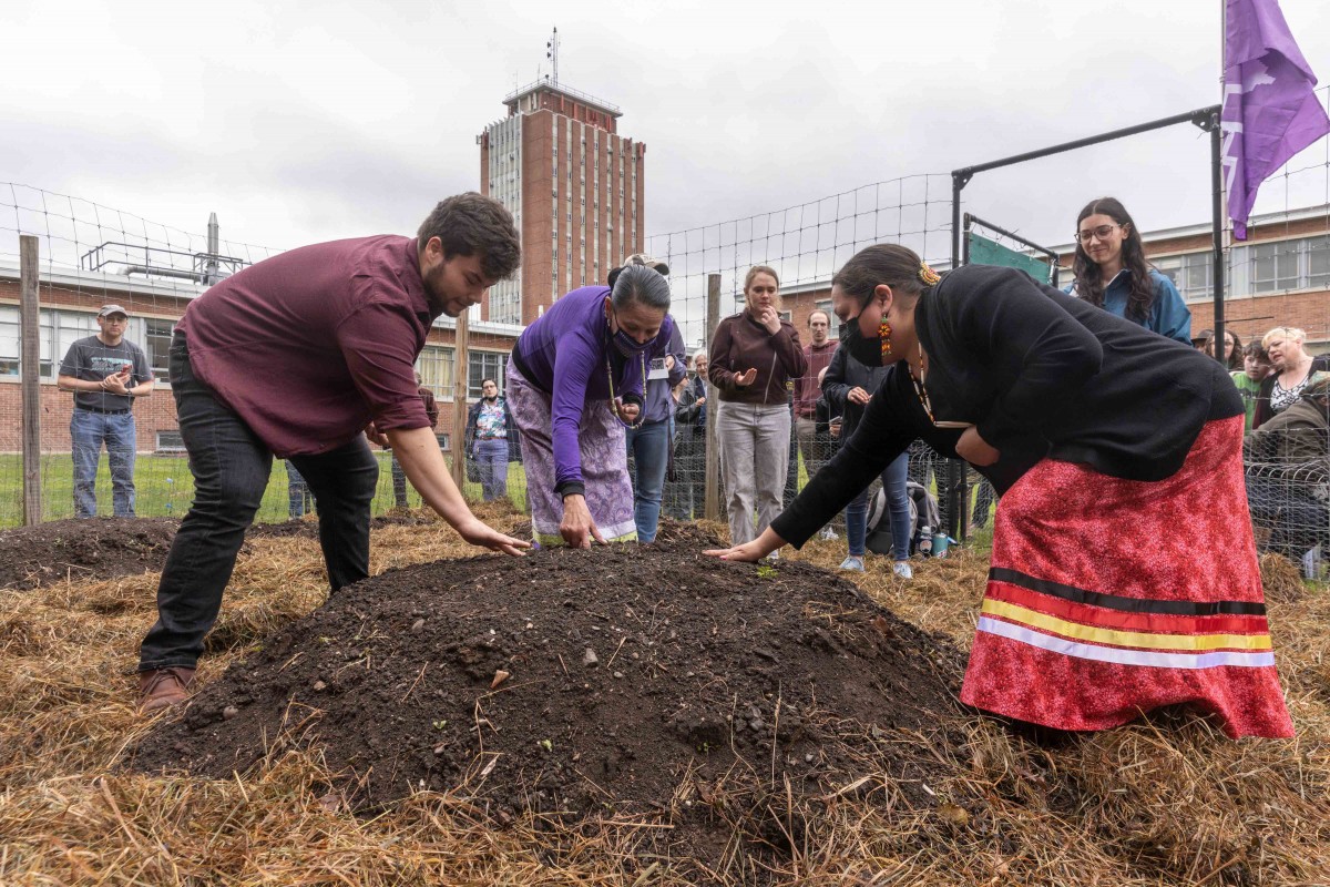 Angela Ferguson, Eel Clan of the Haudenosaunee Confederacy, who supervises the Onondaga Nation Farm, (wearing purple) Sarah Patterson of the Onondaga Nation Farm, (wearing red) Ethan Tyo (Akwesasne Mohawk, wearing red) and Tony Gonyea of the the Onondaga Nation held a traditional Haudenosaunee Thanksgiving blessing of the land and planting of the Three Sisters Garden at the Science I courtyard, Wednesday, May 4, 2022. Members of the Onondaga Nation will return this fall for the harvest and to help the campus community prepare a traditional meal to share. The garden honors the Indigenous peoples who call this land their ancestral home.