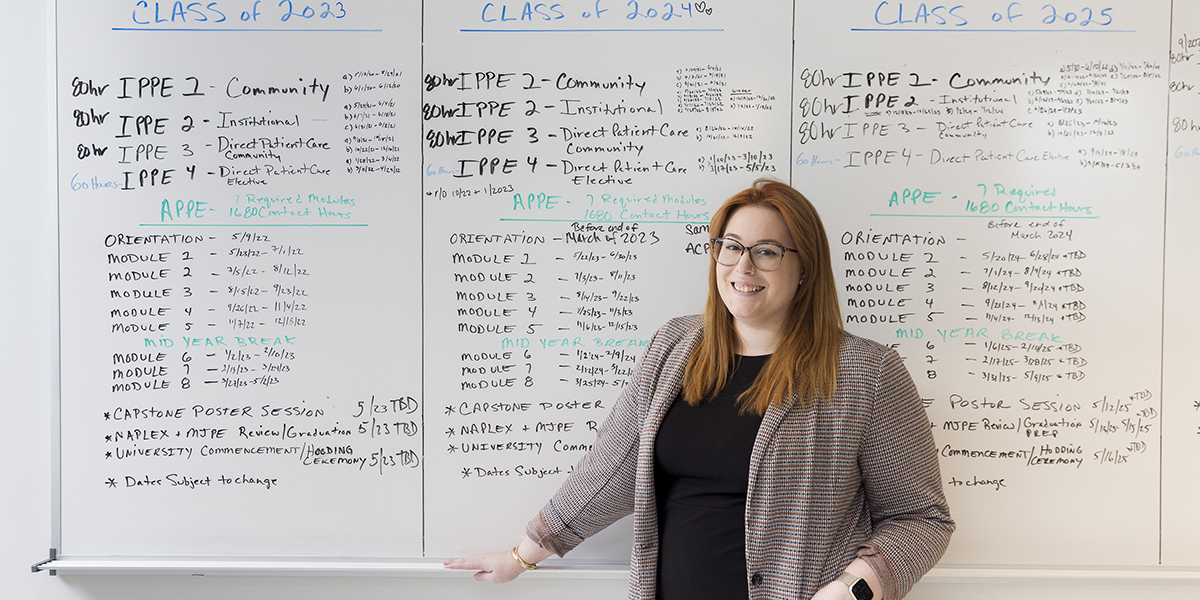 Marissa Langett, experiential specialist with the School of Pharmacy and Pharmaceutical Sciences Office of Experiential Education, stands in front of the flow chart she uses to track student clinical rotations.