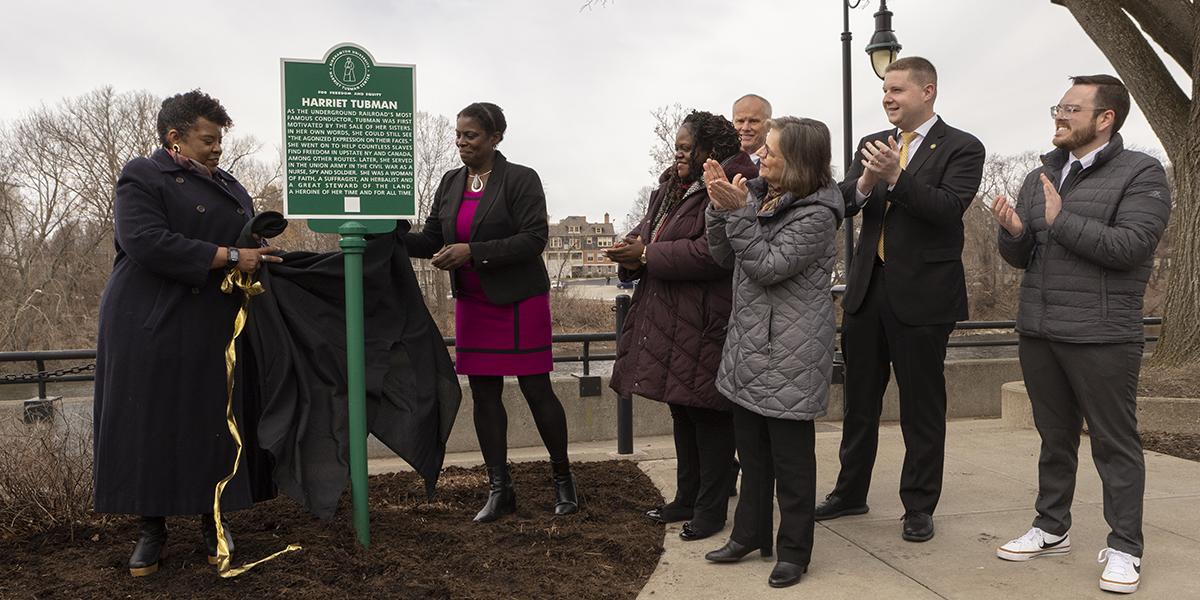 From left, Sharon Bryant and Anne Bailey, associate director and director of the Harriet Tubman Center, respectively, place the first Harriet Tubman Freedom Trail marker outside the Binghamton University Downtown Center. New York State Sen. Lea Webb, Binghamton University President Harvey Stenger, NYS Assemblywoman Donna Lupardo, Binghamton Mayor Jared Kraham and Gov. Kathy Hochul representative Harris Weiss look on.