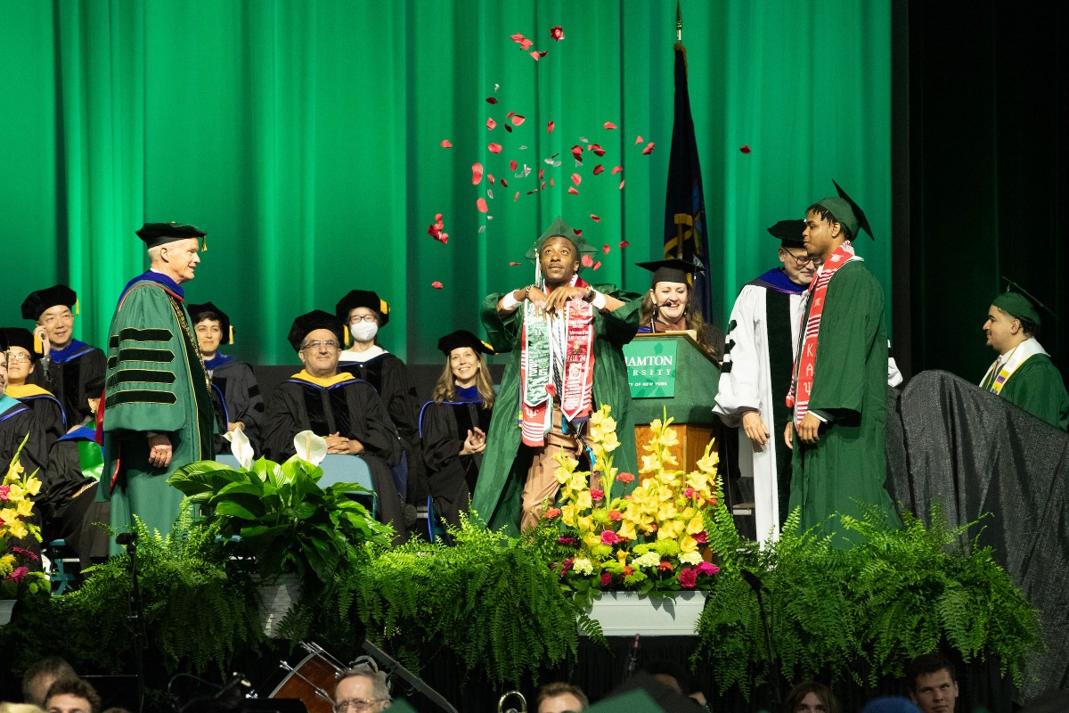 A graduate walks across the stage in a shower of flower petals during the second Harpur Commencement ceremony on May 17, 2025.