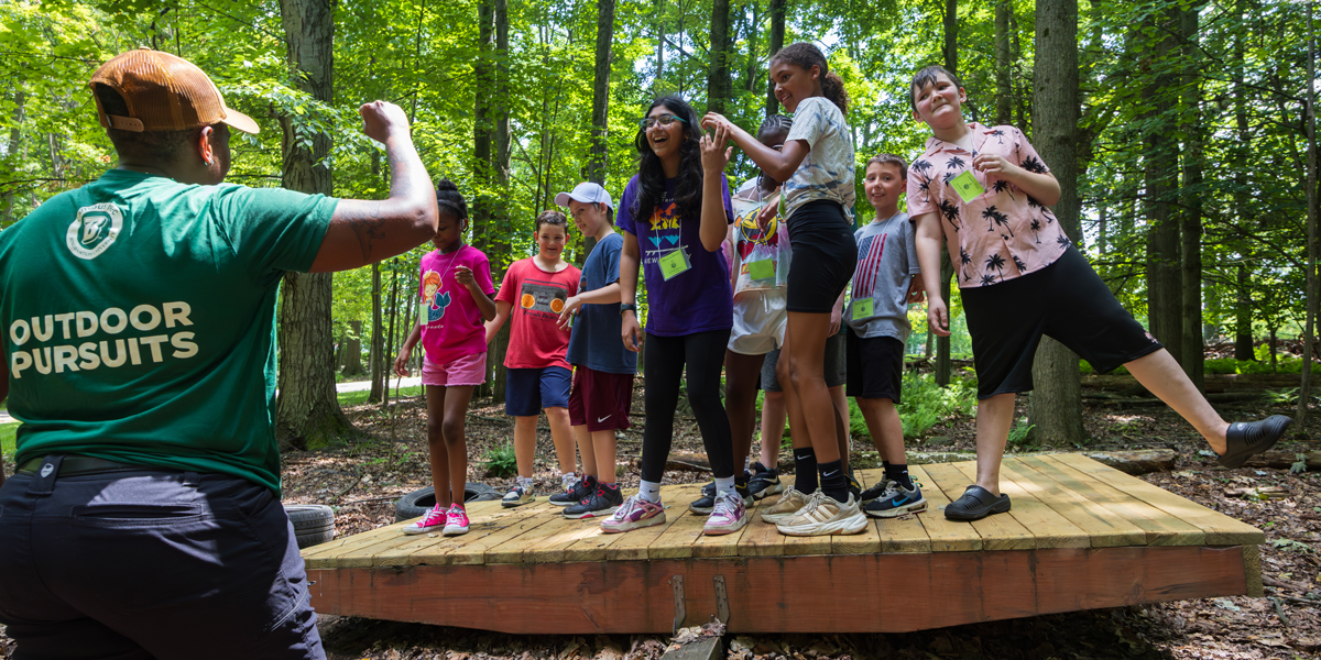 Local middle school students participating in Binghamton University's Go Green Institute, an intensive 10-day, hands-on learning experience centered on the theme of a greener living environment, learn team-building skills taught by Campus Recreation's Outdoor Pursuits staff at the West Gym Ropes Course.