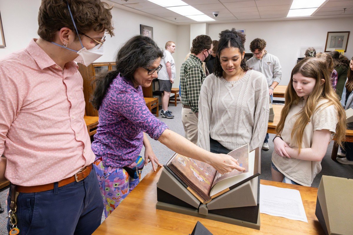 Faculty from Harpur College of Arts and Sciences' Department of Middle Eastern and Ancient Mediterranean Studies hosted a community outreach event with 16 Chenango Valley High School students. Pictured here, Lark Wilson, Special Collections Librarian for Instruction, Reference and Engagement and Tina Chronopoulos, Associate Professor/Chair of MEAMS, show 10th-graders Kyra Bolden and Sydney Anderson a medieval manuscript.
