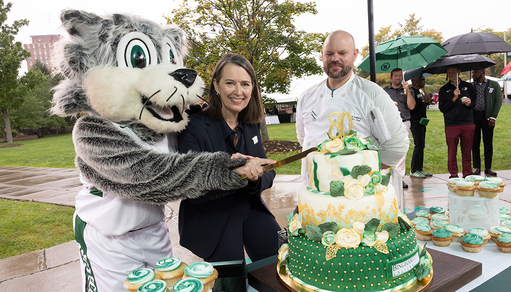 President Anne D'Alleva, Pastry Chef Paul Kellems and Baxter the Bearcat cut the 80th anniversary cake on the Peace Quad to celebrate Binghamton University's 80th birthday, Oct 1, 2026.