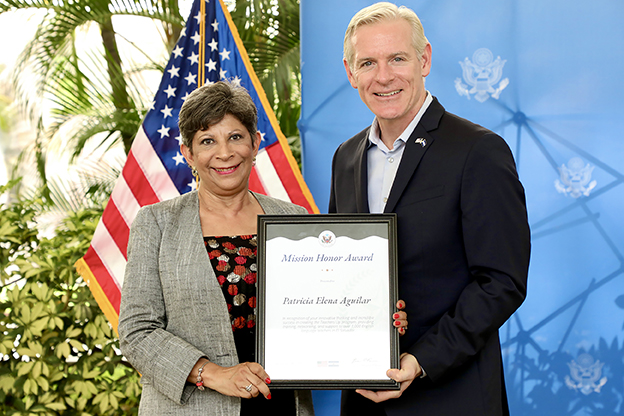 Patricia Aguilar, MA ’93, receives the Mission Honor Award from Brendan O’Brien, former chargé d’affaires, at the U.S. Embassy in El Salvador.