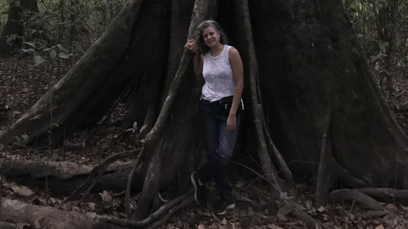 Binghamton University Associate Professor of Comparative Literature Giovanna Montenegro stands next to a Mora tree in Guyana.