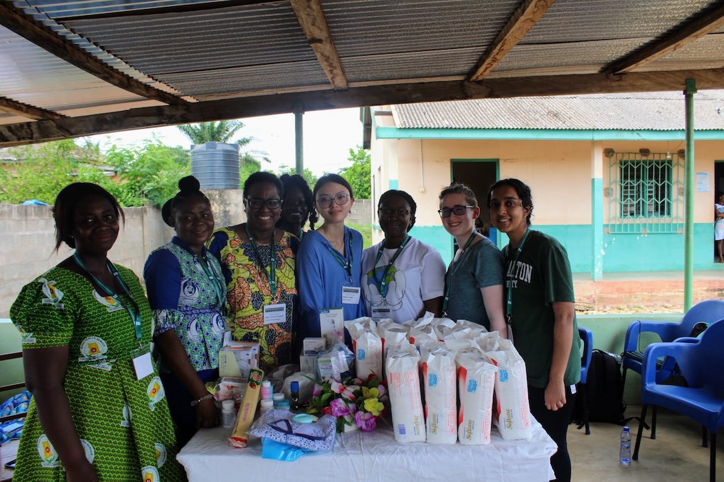 Zhiqiao Huang (center), and Associate Professor Titi Okoror (center left) stand with other members of the research team — including two nurses at the Child Welfare Center (CWC) at Hohoe, Ghana and students Farida Larry, Meghan Westpfal and Yasmeen Gilani — next to a table of products for mothers and infants.