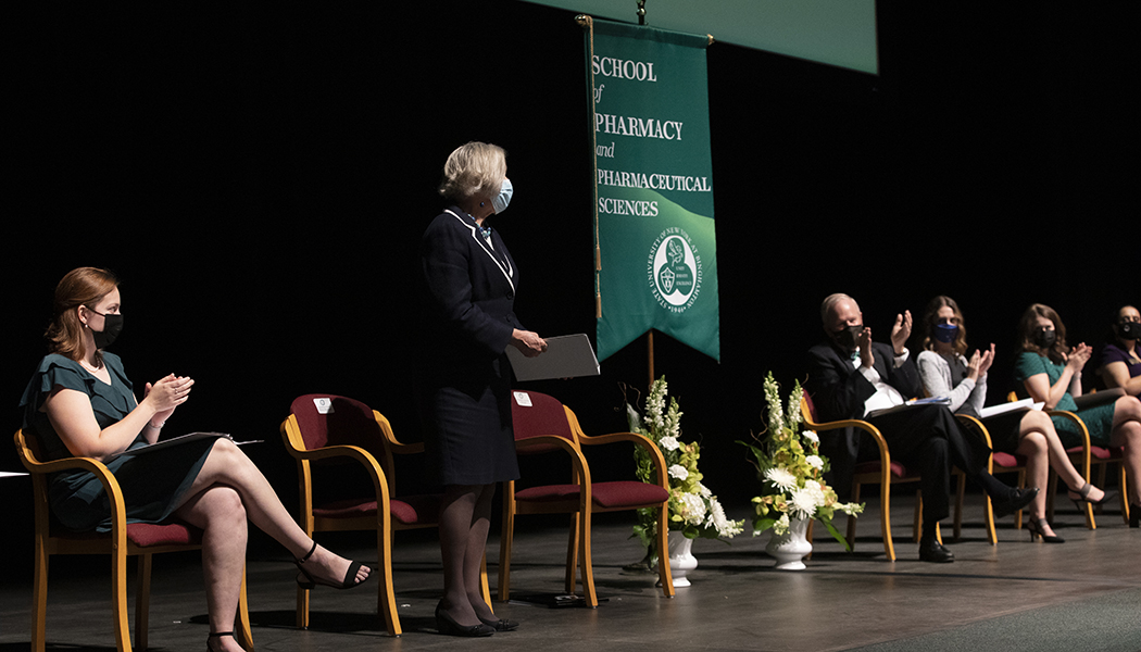 Gloria Meredith, founding dean of the School of Pharmacy and Pharmaceutical Sciences, is applauded during a tribute to her during the school's fifth, and her final, White Coat Ceremony.