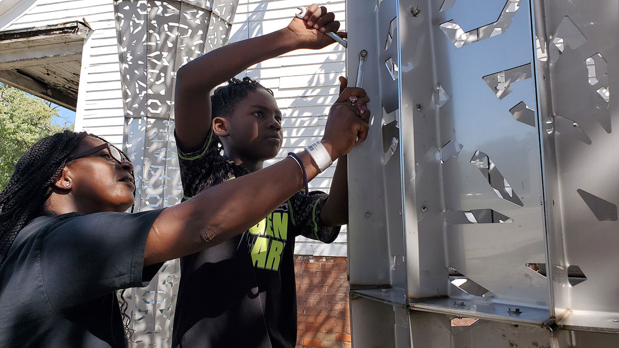 A grandmother and grandchild work on the American Riad, a public sculpture in Detroit.