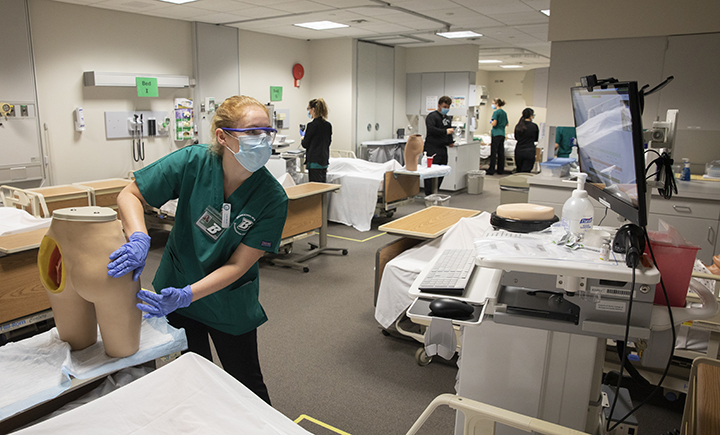 Undergraduate nursing students were divided into small groups to reduce density in the Innovative Simulation and Practice Center. They are also socially distanced and wearing masks.