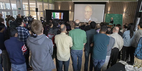 Distinguished Professor M. Stanley Whittingham speaks by video conference to a crowd gathered at the Smart Energy Building about his Nobel Prize in Chemistry. Whittingham was at a scientific meeting in Germany when the prize was announced.