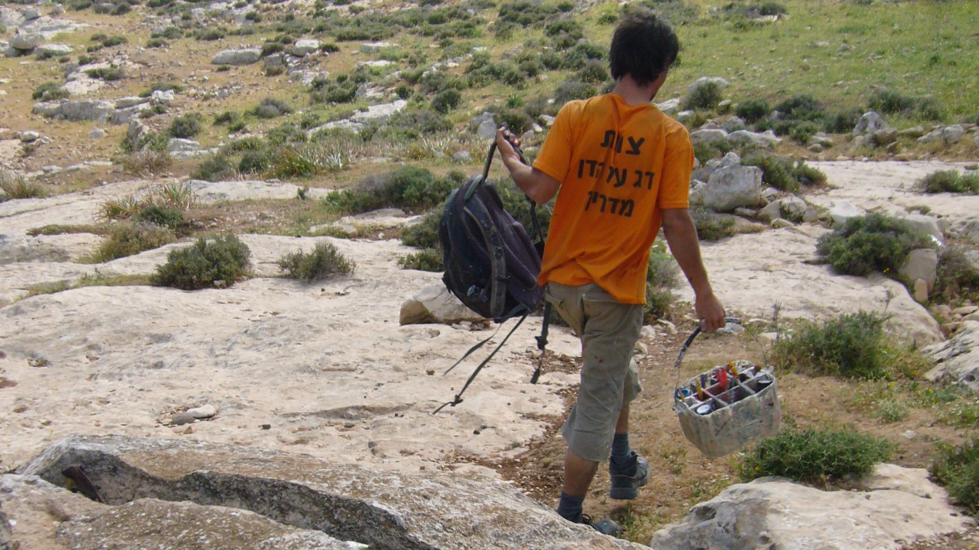 An Israeli waymarking crew member walks down a hiking path after he just painted a blue blaze on a rock.