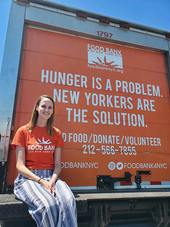 Jessica Presedo sits on the back of a Food Bank for New York City truck.