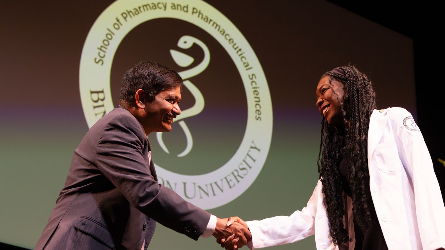 Dean and SUNY Distinguished Professor Kanneboyina Nagaraju shaking hands with a new pharmacy student at the 2025 White Coat Ceremony.