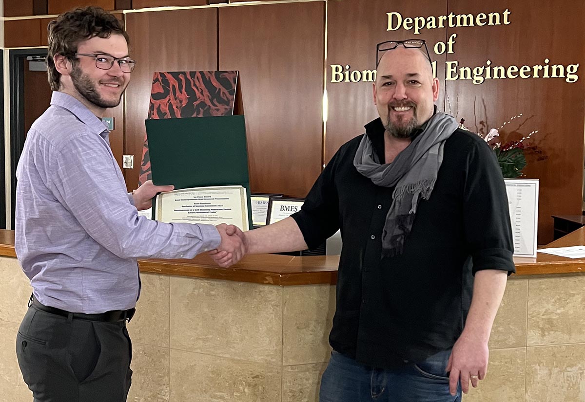 Ray Goodman receives the Biomedical Engineering Research Expo's Best Graduate Research Oral Presentation Award from Associate Professor Guy German.