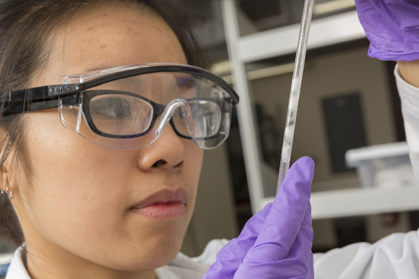 Binghamton University doctoral student Carrie Siu inspects a sample in the laboratories of the NorthEast Center for Chemical Energy Storage.