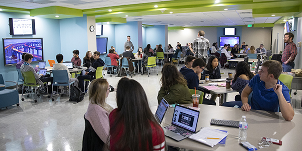 Students of the First-Year Research Immersion program take Harpur 170, “Seminar of Research Methods” taught by Timothy S. de Smet, standing far right, research assistant professor, and Jonathan Schmitkons, with back to the camera, research assistant professor, at the program’s classroom in the Glenn G. Bartle Library.