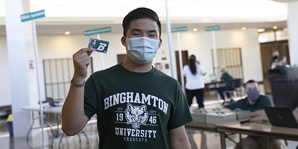 Incoming student Gabriel Wong proudly displays his Binghamton University ID card before picking up his room key at the West Gym during Move-in Week.