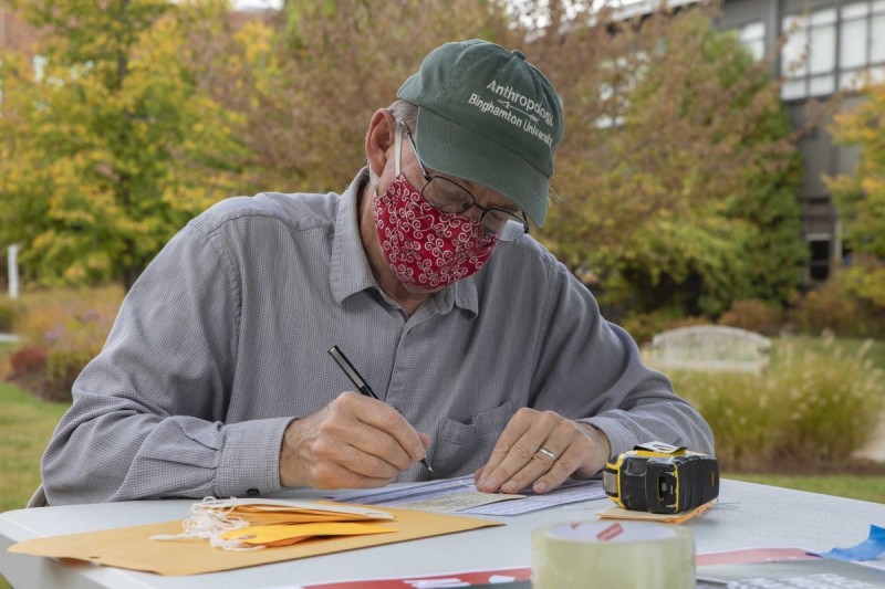 Distinguished Professor of Anthropology Randall McGuire fills out toe tags for an art exhibit showcasing the plight of migrants along the United States' southern border.
