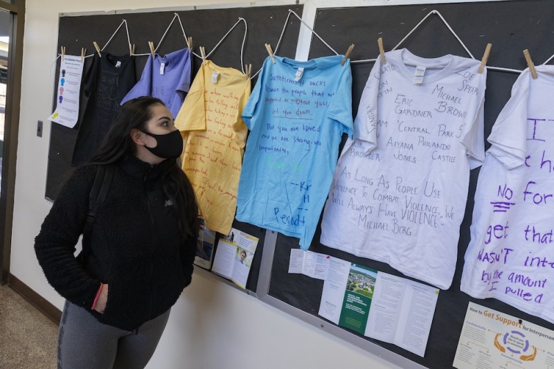 Hanny Mendoza reads messages on t-shirts that make up the Clothesline Project displayed at the West Gym, Monday, April 5, 2021.