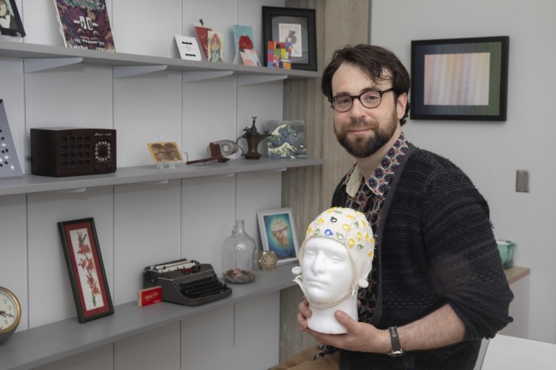 Assistant Professor of Psychology Nicholas Gaspelin holds an electroencephalography cap.