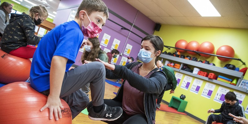 Anna Pearlman, a senior majoring in mathematical sciences and minoring in Spanish and education, does exercises with a young boy who has Down Syndrome at GiGi's Playhouse, helping him to strengthen his muscles.