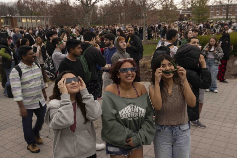 A crowd on the Quad gathers to watch the solar eclipse during its peak.