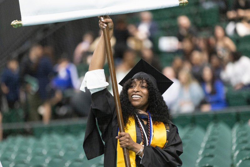 Student holds department banner during academic procession.