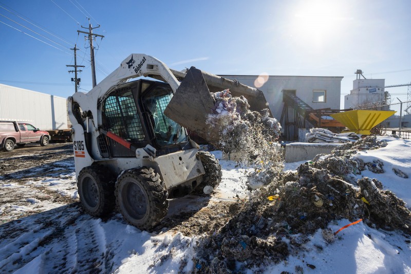 Jacob Kumpon ’22 drives a small bulldozer at the KLAW Industries facility in Binghamton, where recycled waste is turned into a concrete-strengthening material.