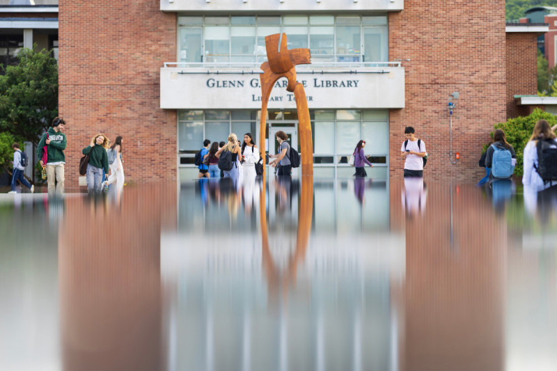 Students walk by the fountain at Harpur Quad by the Glenn G. Bartle Library Tower.