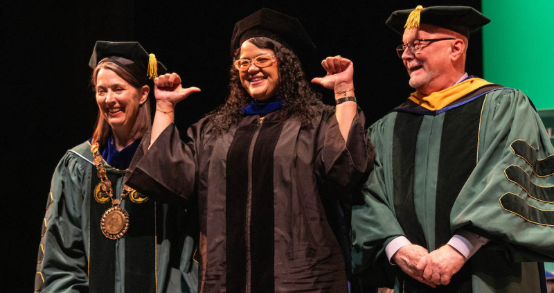 A graduate celebrates with Binghamton University President Anne D'Alleva and Provost Donald Hall during the doctoral hooding ceremony Thursday.