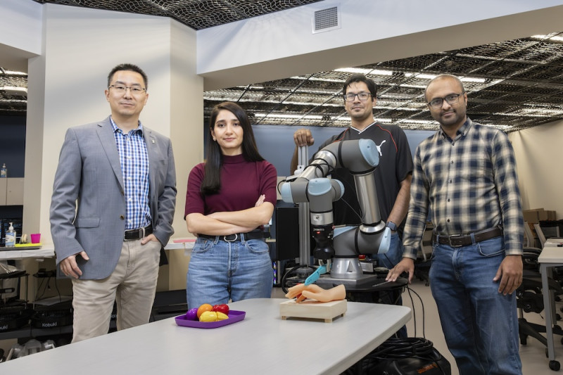 Computer scientists at the Watson College of Engineering and Applied Science pose with a mobile robot they use to conduct their research on robot security. From left to right: Associate Professor Shiqi Zhang, PhD student Zainab Altaweel, PhD student Mohaiminul Al Nahian, and Assistant Professor Adnan Siraj Rakin.