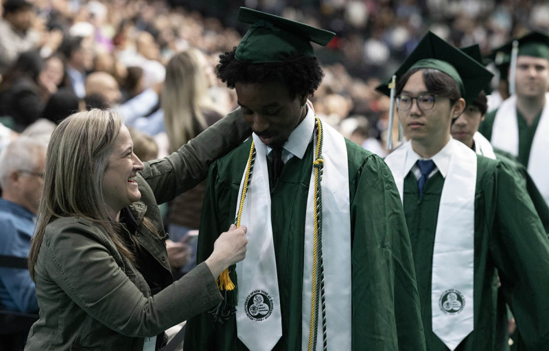 Stacey Brown, assistant director of the Watson Career and Alumni Connections office, helps a student with a last-minute wardrobe adjustment at the 2026 Commencement ceremony for Binghamton University's Thomas J. Watson College of Engineering and Applied Science.