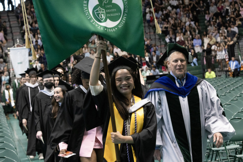 A Harpur student holds a banner during the entry procession in the third Commencement ceremony of May 16, 2026.