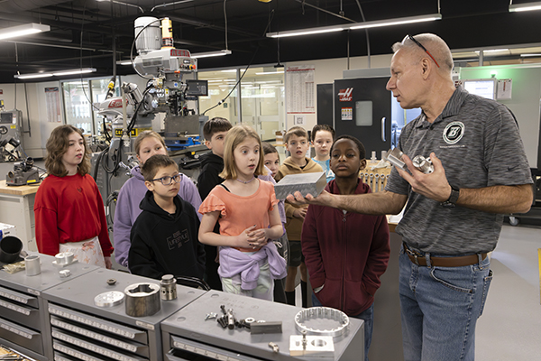 Students from Glenwood Elementary School in Vestal, N.Y., watch as Bob Pulz, an instructional support technician, displays pieces of metal used in additive manufacturing at the Watson Fabrication Lab during a Binghamton University field trip in March. Students from each elementary school in the Vestal Central School District toured the campus in the spring.
