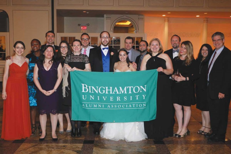 Knowing there would be quite a few Binghamton alumni at the wedding, Brian asked the Alumni Association for a school banner to use in some of the photos. Pictured here, from left: Sara (Miller) Fox ’09, Lois Young ’06, Diane Napolitano ’06, Mike Schordine ’05, Katherine McCrink ’06, Amber Beckley Largeaud ’06, Jared Gilman ’08, Brian Miller ’05, Meryl (Mandelbaum) Miller ’10, Jason Wand ’06, Joe Frankino ’05, Lindsey (Krecko) Yates ’04, Rich Ziolkowski ’04, Nicole (Papadopoulos) Ziolkowski ’04, Jennifer Katz ’05 and Josh Shapiro ’03. Also in attendance, but not pictured: Marissa (Forman) Wright ’05, and Jeremy Wright and Beth (Kaufman) Solomon, both ’06.
