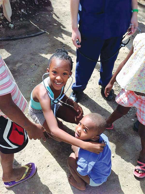 Siblings living in the San Pedro de Macorís province of the Dominican Republic listen to their heartbeats during a training conducted by Decker School students to help children accept a physical examination.