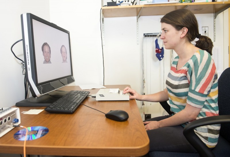 A woman has her pupil dilation measured while she watches various facial expressions on a computer.