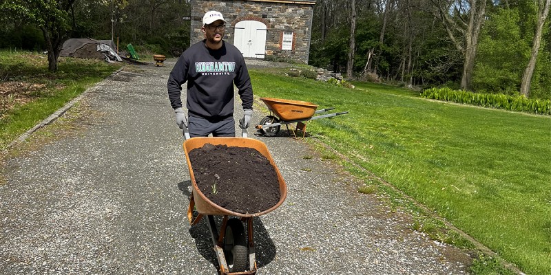 Darwin Martinez '11, MBA '16 moves mulch during an Alumni Global Day of Service event.