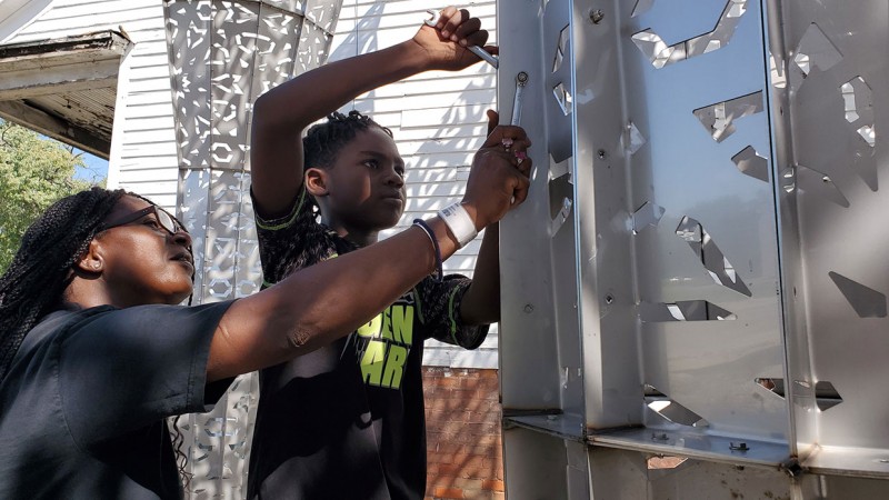 A grandmother and grandchild work on the American Riad, a public sculpture in Detroit.