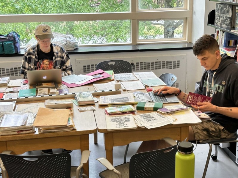 Eden Lowinger ’23, MSW ’25 and Casey Adrian ’22, MSW ’24 (right) catalog materials associated with Gay Men’s Health Crisis (GMHC), the world’s first major HIV/AIDS service organization.