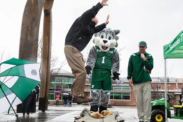 Vice President for Student Affairs Brian Rose steps (stomps!) on the coat as the campus reenacts an annual tradition that says spring has sprung. Dave Simek, associate director of athletics and chair of the campus Spirit Committee, and Baxter, look on.