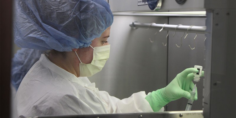 UHS pharmacy technician Katie Sasina draws a syringe in the pharmacy's sterile compounder