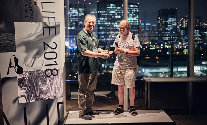 Professor Hiroki Sayama receiving the Best Paper of the Decade award from the International Society of Artificial Life (ISAL).