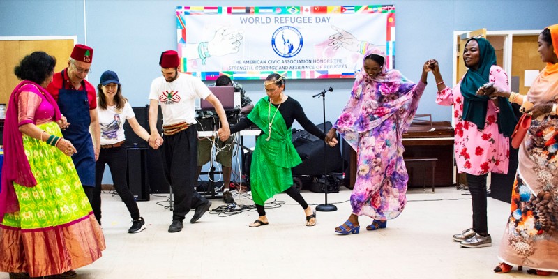Attendees of an All Nations Celebration event held by the American Civic Association in Binghamton join together in dance, wearing traditional attire representing their countries of origin.