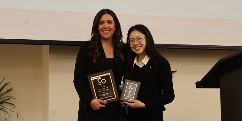 Associate Dean Sara Wozniak (left) accepts the Excellence in Career Integration Award in the school/college category during the 2026 Career Champions Breakfast in March. Allison Pham, a senior nursing student, presented the award.